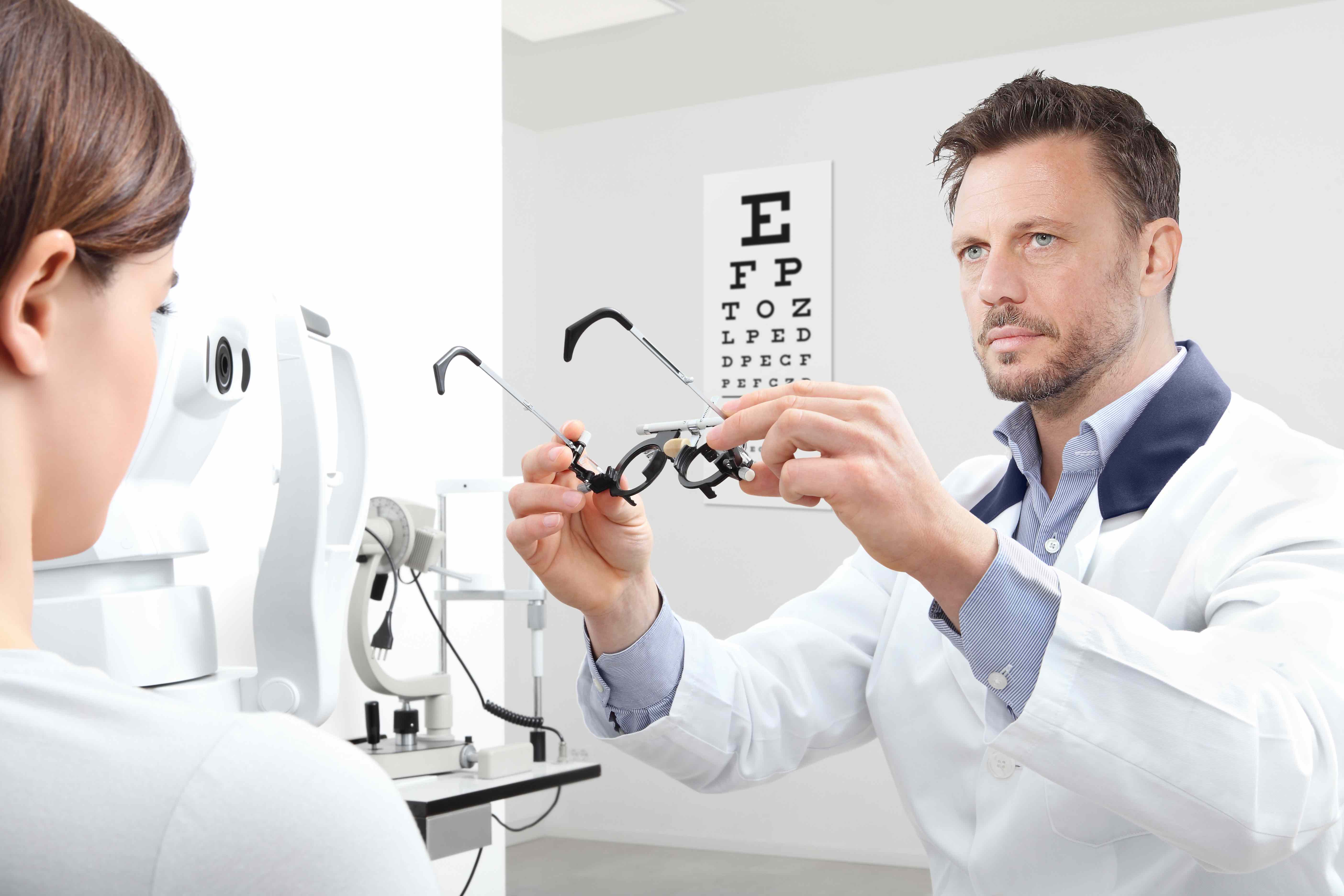 optometrist with trial frame examining eyesight woman patient in optician office Newsom Eye